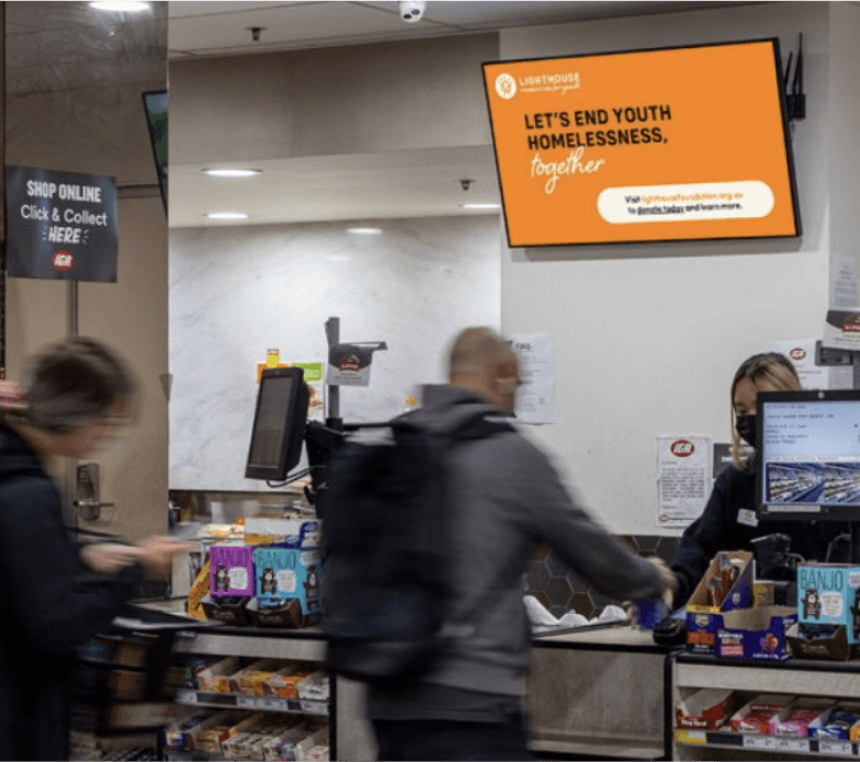 A digital advertising screen above the checkout in a local supermarket